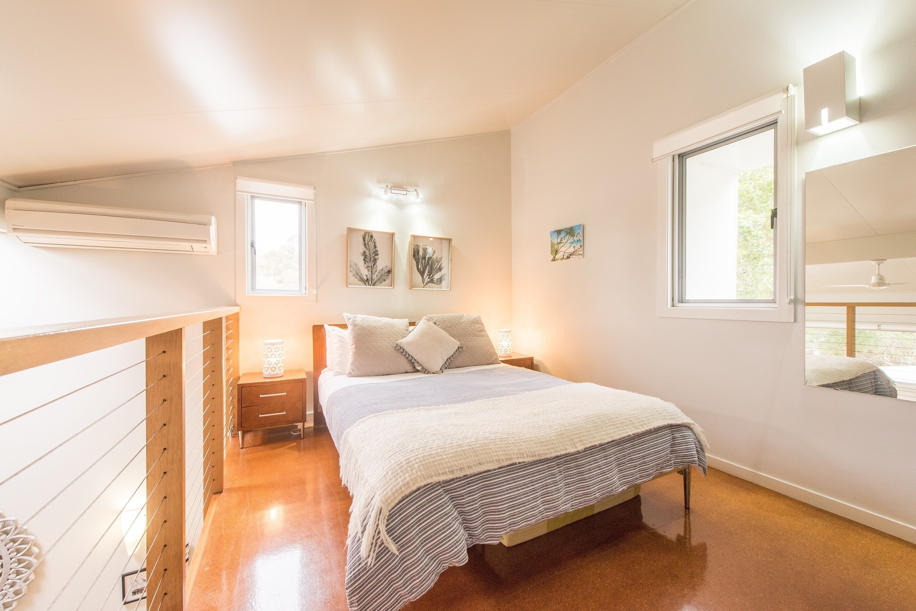 A bedroom with a bed, bedside tables, a window, and wall-mounted artwork.