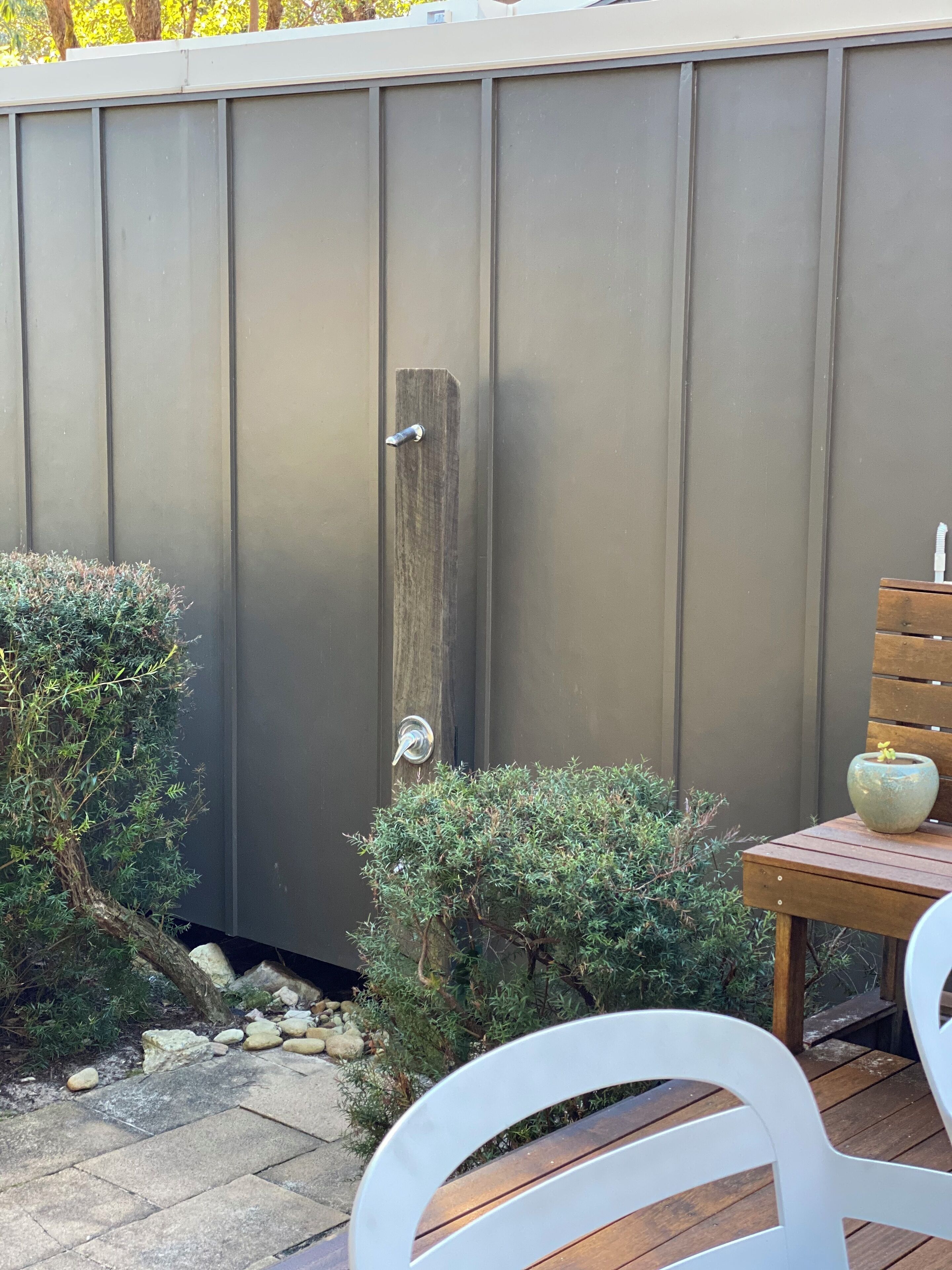 A wooden deck with a metal fence, a small table with a vase, and a chair.
