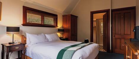 Un dormitorio ordenado con cama, mesitas de noche, lámpara y armario.
