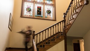 A staircase with wooden railings and a stained glass window above. - Franklin Manor (Strahan)