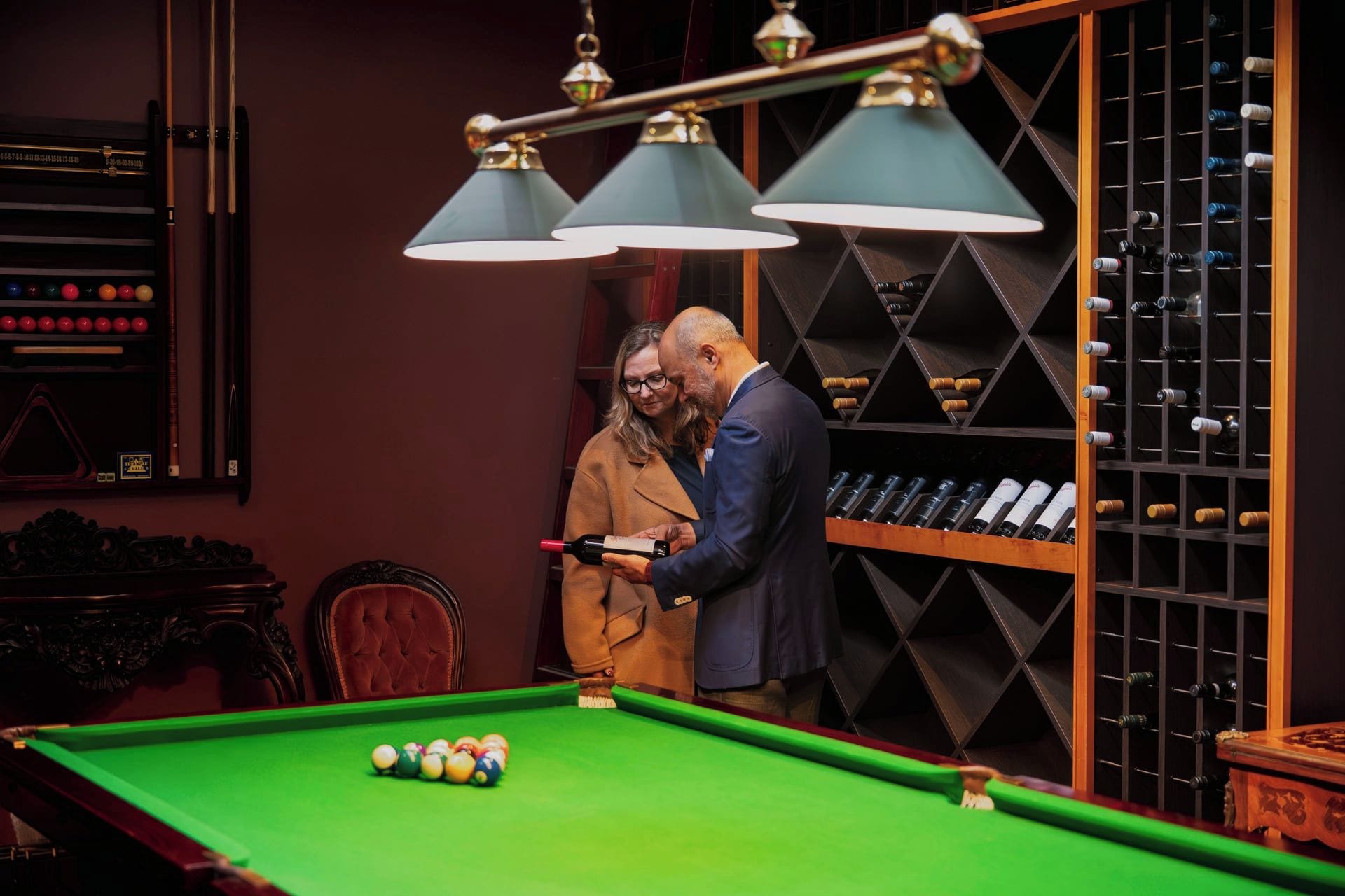 A billiards table with balls, a wine rack, and a clock.