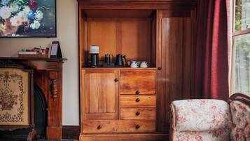 A wooden cabinet with drawers, a coffee maker, and teapots on top.