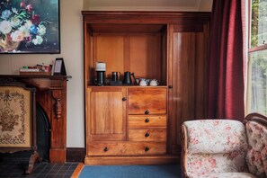 A wooden cabinet with drawers, a coffee maker, and teapots on top. - Franklin Manor (Strahan)
