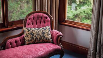 A chair with a patterned cushion in a room with a window and curtains.