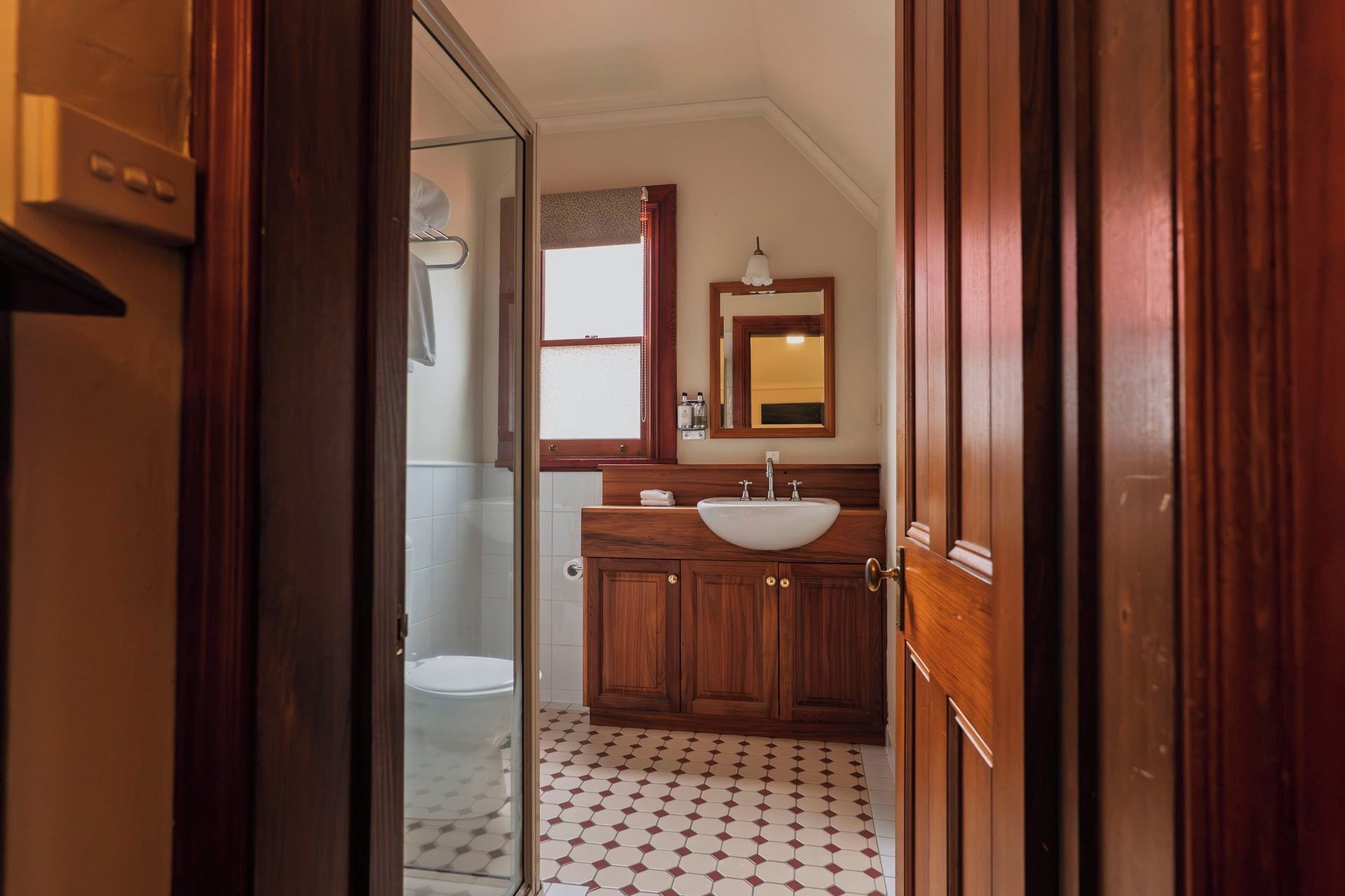 Un baño con tocador de madera, lavabo y espejo.