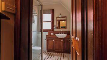 Un baño con tocador de madera, lavabo y espejo.
