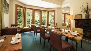 A dining area with a long table, multiple chairs, and a fireplace. - Franklin Manor (Strahan)
