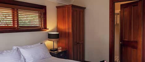 A bedroom with a bed, a nightstand, a lamp, a wardrobe, and a door.