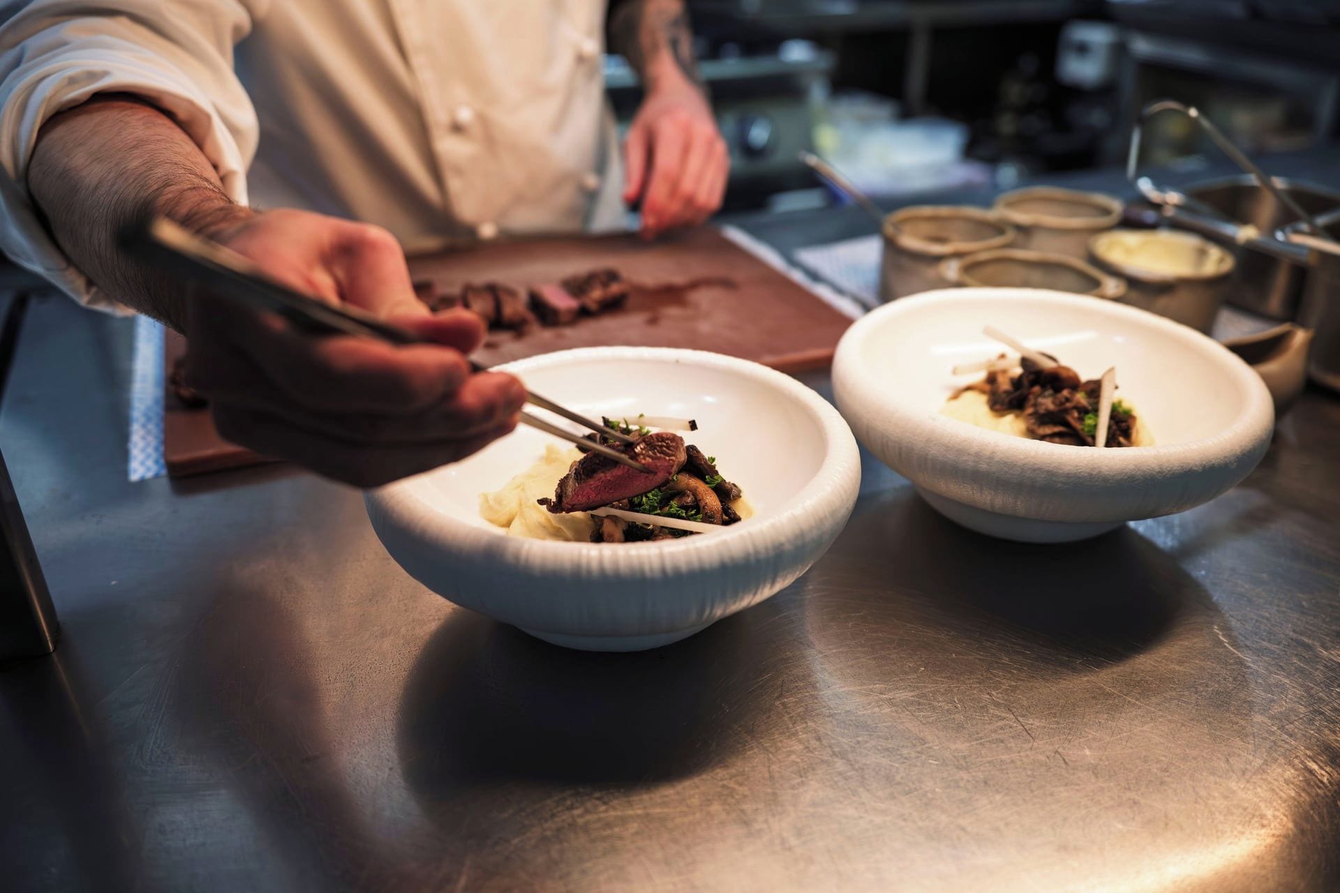 A chef preparing food with a focus on the dish and utensils.