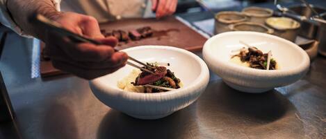 A chef preparing food with a focus on the dish and utensils.