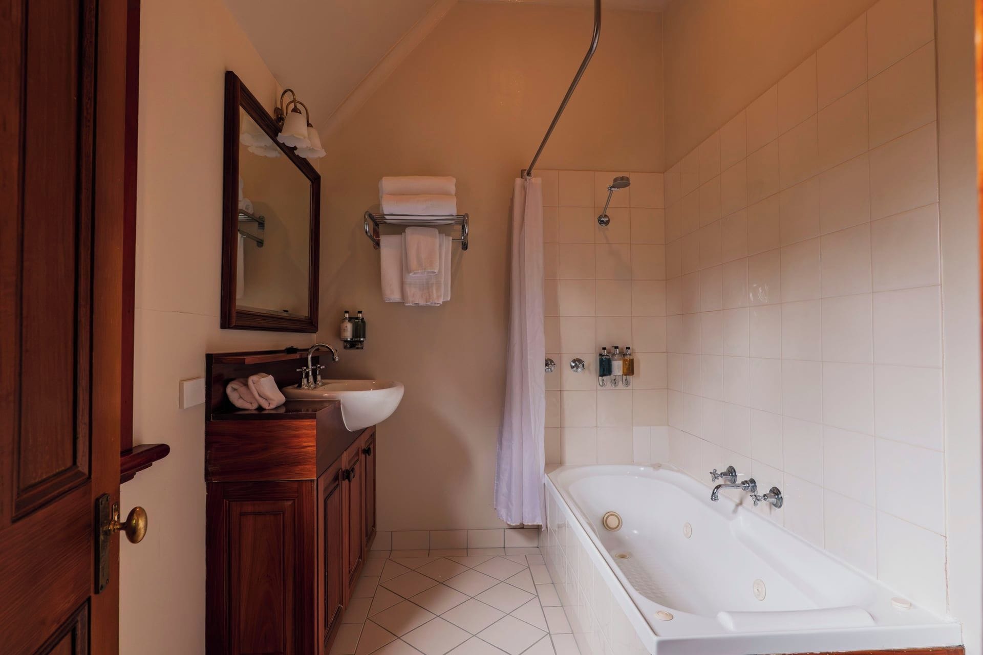 A bathroom with a wooden vanity, a large mirror, a bathtub, and a shower area.