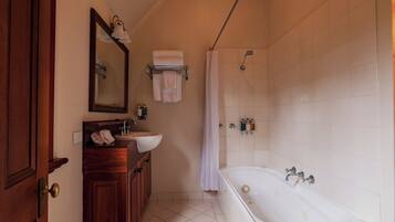 A bathroom with a wooden vanity, a large mirror, a bathtub, and a shower area.