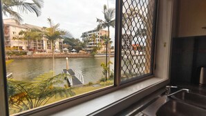 A view from a window overlooking a body of water with palm trees and buildings in the background. - K Resort (Surfers Paradise)