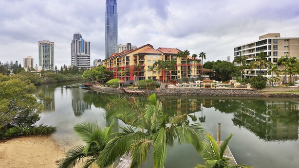 A waterfront hotel with a view of a river, palm trees, and high-rise buildings in the background. - K Resort (Surfers Paradise)