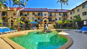 A resort pool area with clear water, blue lounge chairs, and a sign indicating a no-smoking zone. - K Resort (Surfers Paradise)