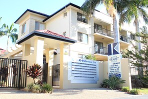A multi-story hotel with balconies, a sign indicating a vacancy, and a private beach.