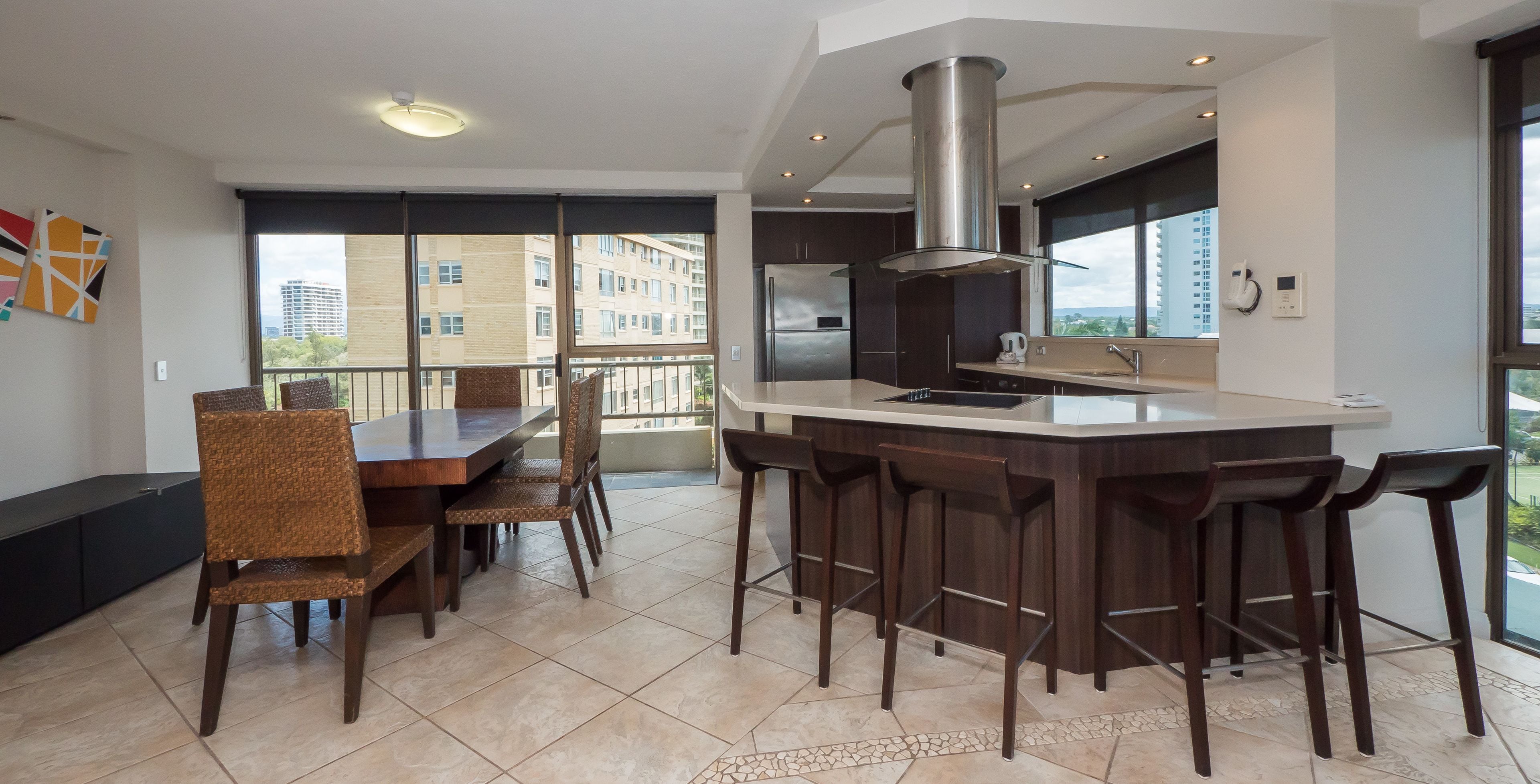 Une cuisine moderne avec un îlot central, des chaises en bois foncé et une table à manger.
