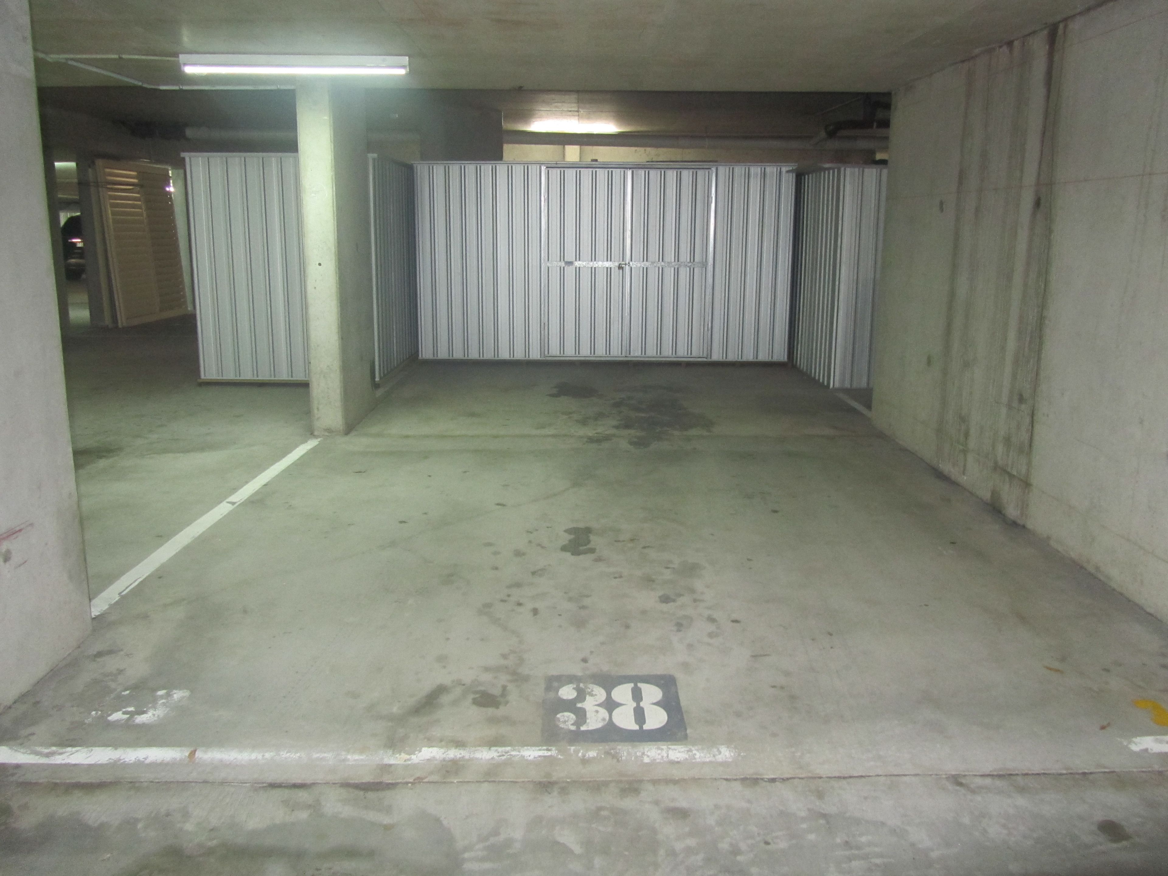 A parking garage with concrete floors, metal walls, and a number 38 marking.