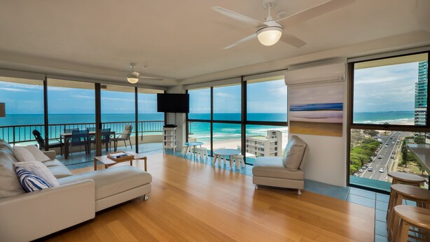 Un vaste salon avec un grand balcon offrant une vue imprenable sur la plage et l’océan.