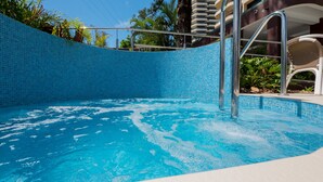 Une piscine aux carreaux bleus, entourée d’un bâtiment doté de balcons.