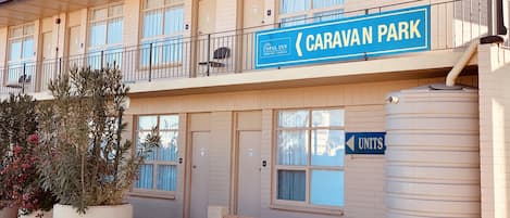 A two-story motel with a sign for 'Caravan Park' and 'Opal Inn' indicating motel rooms on the left and units on the right.