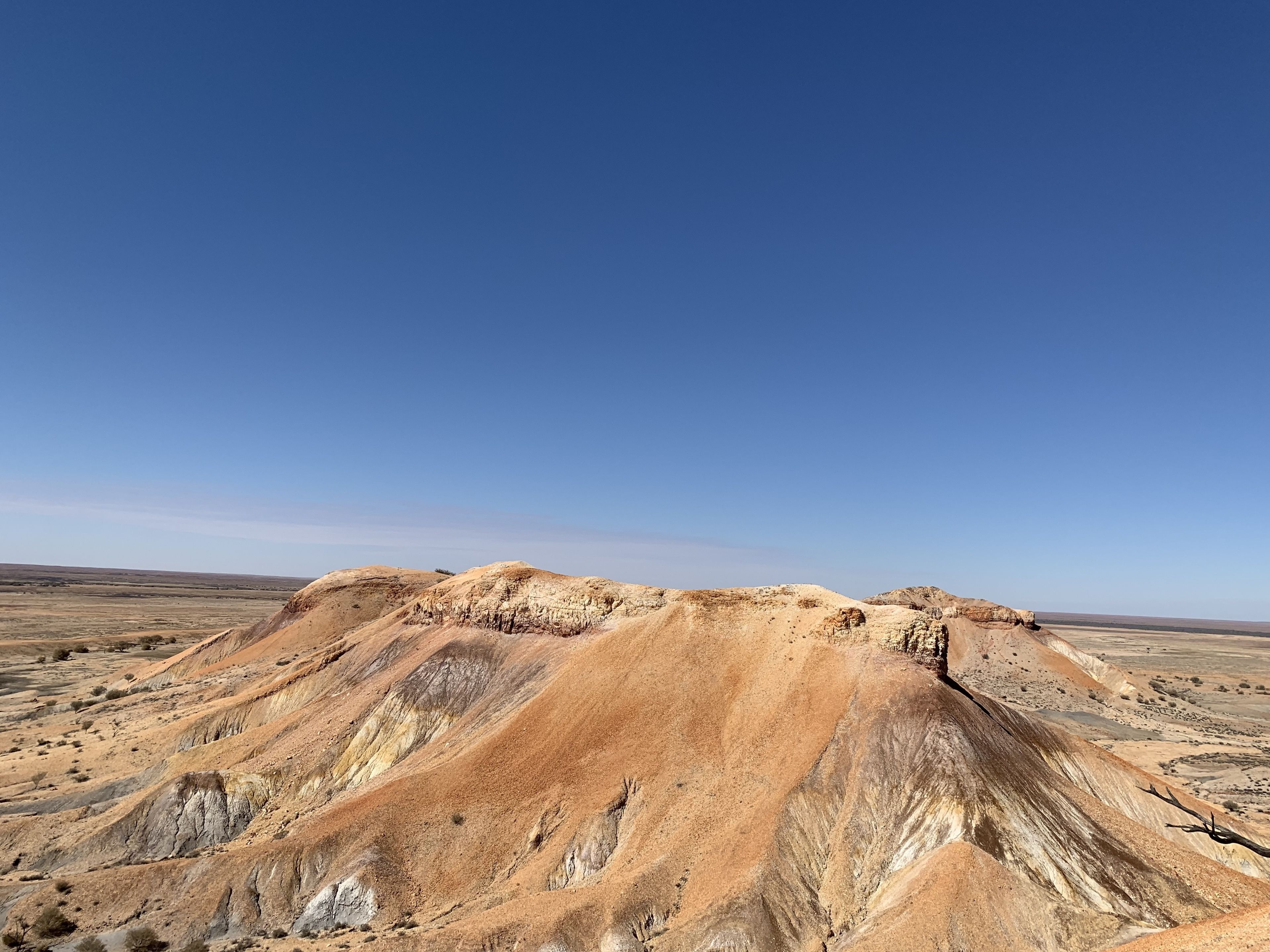 A vast, arid landscape with rolling hills and sparse vegetation under a clear blue sky.