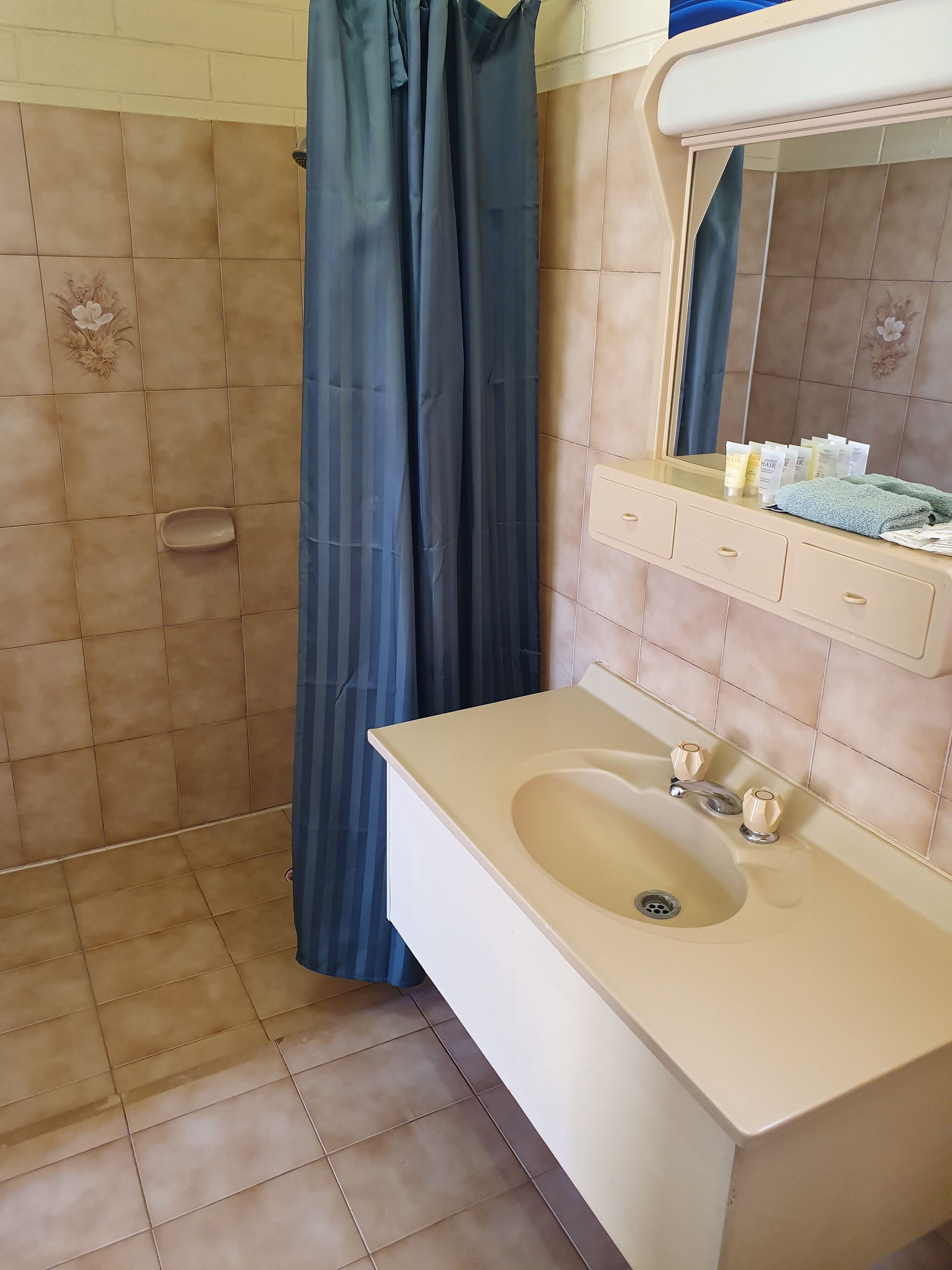 A bathroom with a beige sink, a mirror, and a shower curtain.