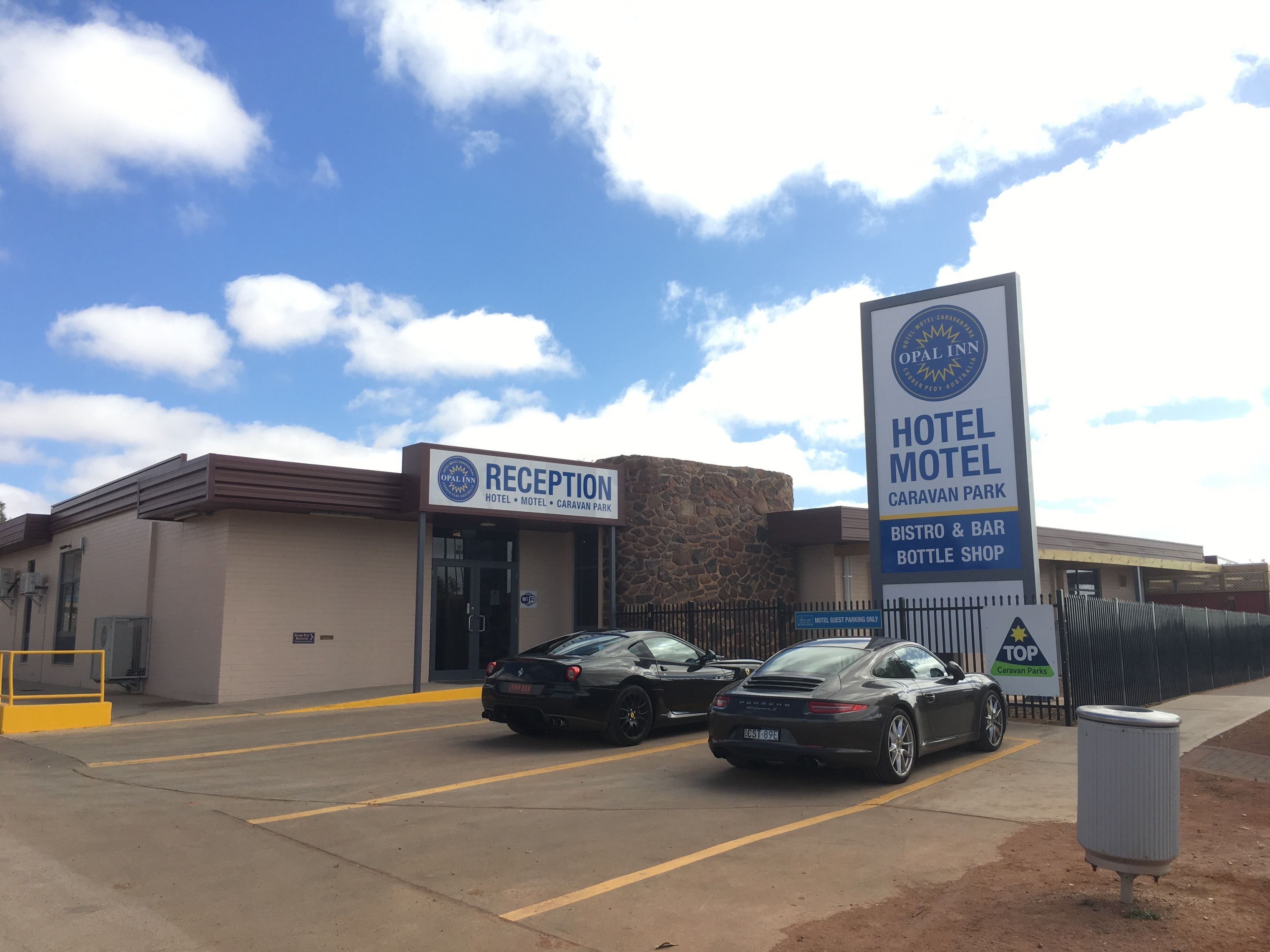 A hotel reception with a sign for the Opal Inn, including amenities like a bistro, bar, and bottle shop.