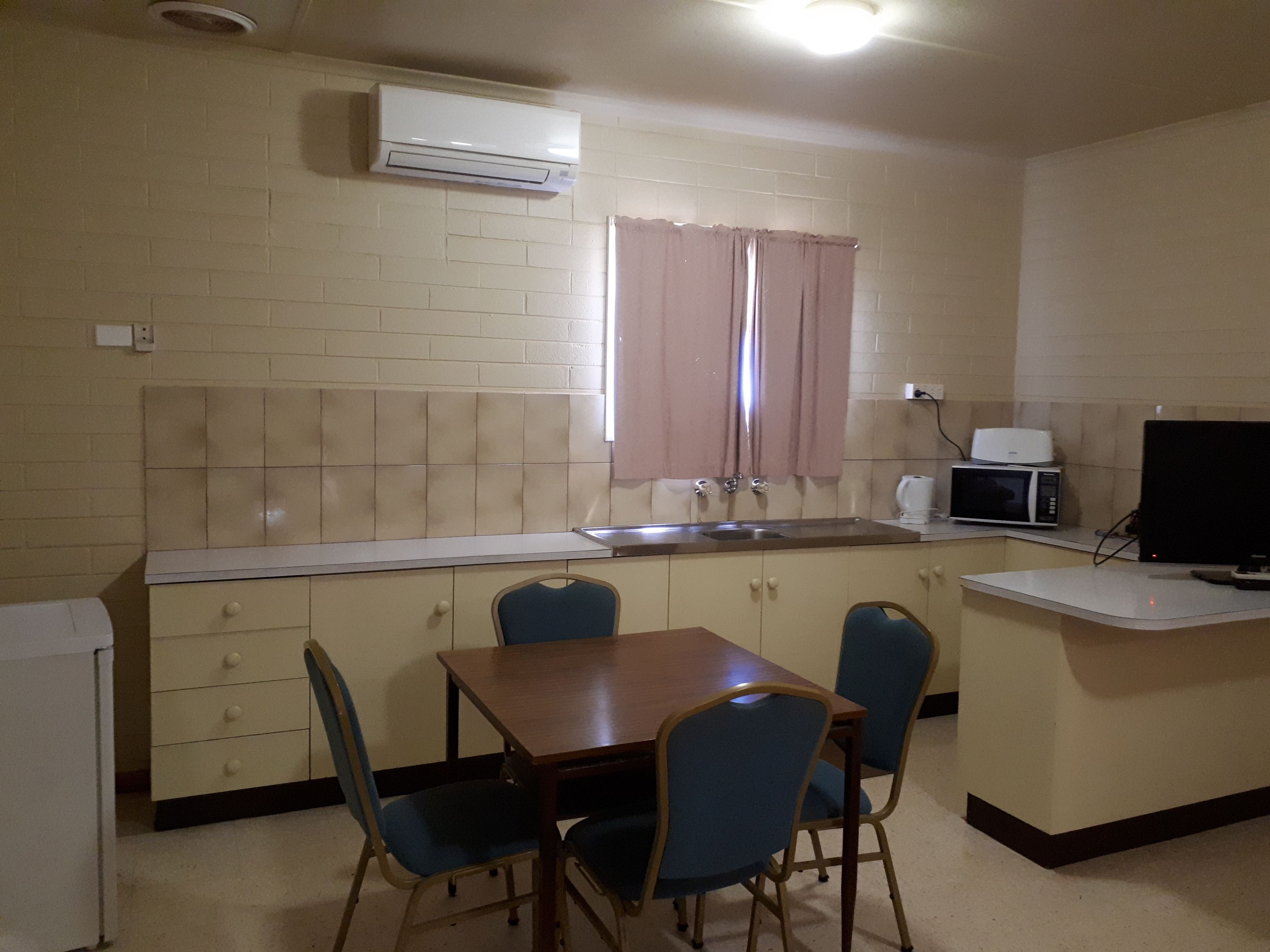 Cocina compacta con comedor, que incluye un fregadero, microondas y televisor de pantalla plana.