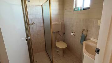 Un baño pequeño con inodoro, lavamanos y ducha.