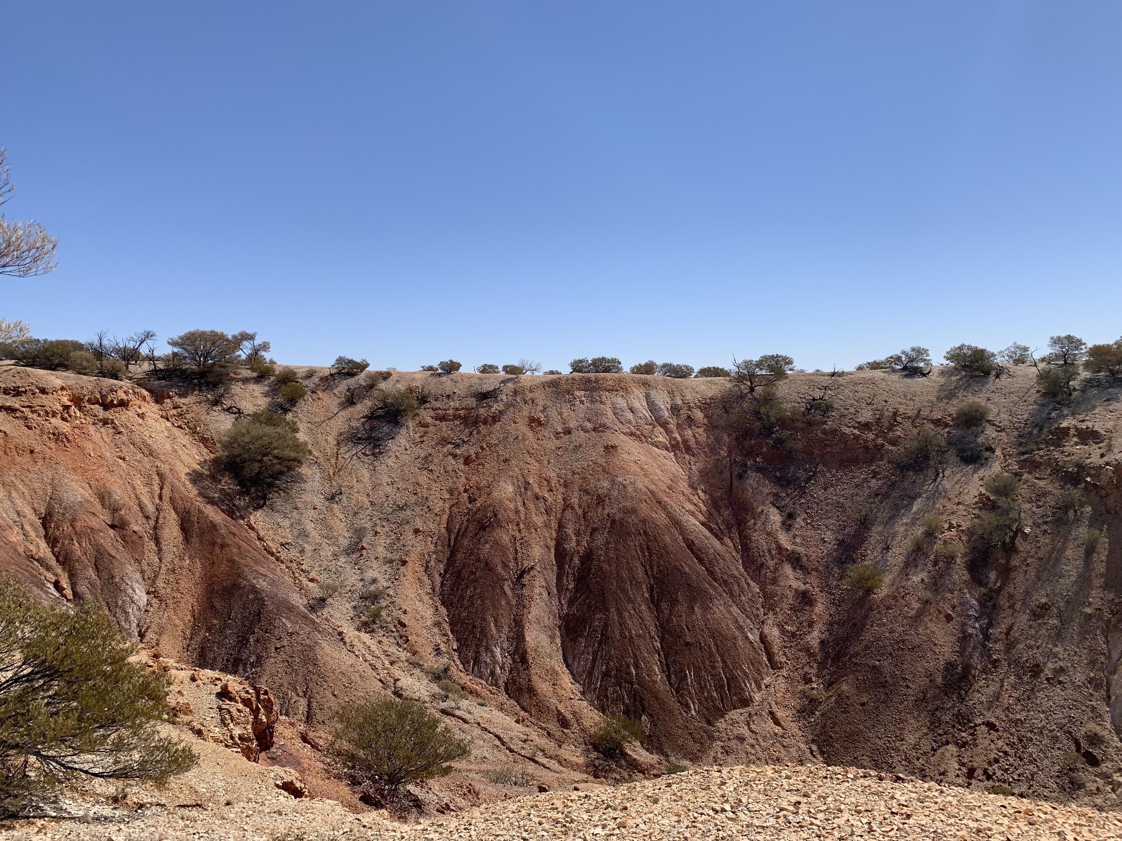 A rugged cliff with sparse vegetation and a clear sky.