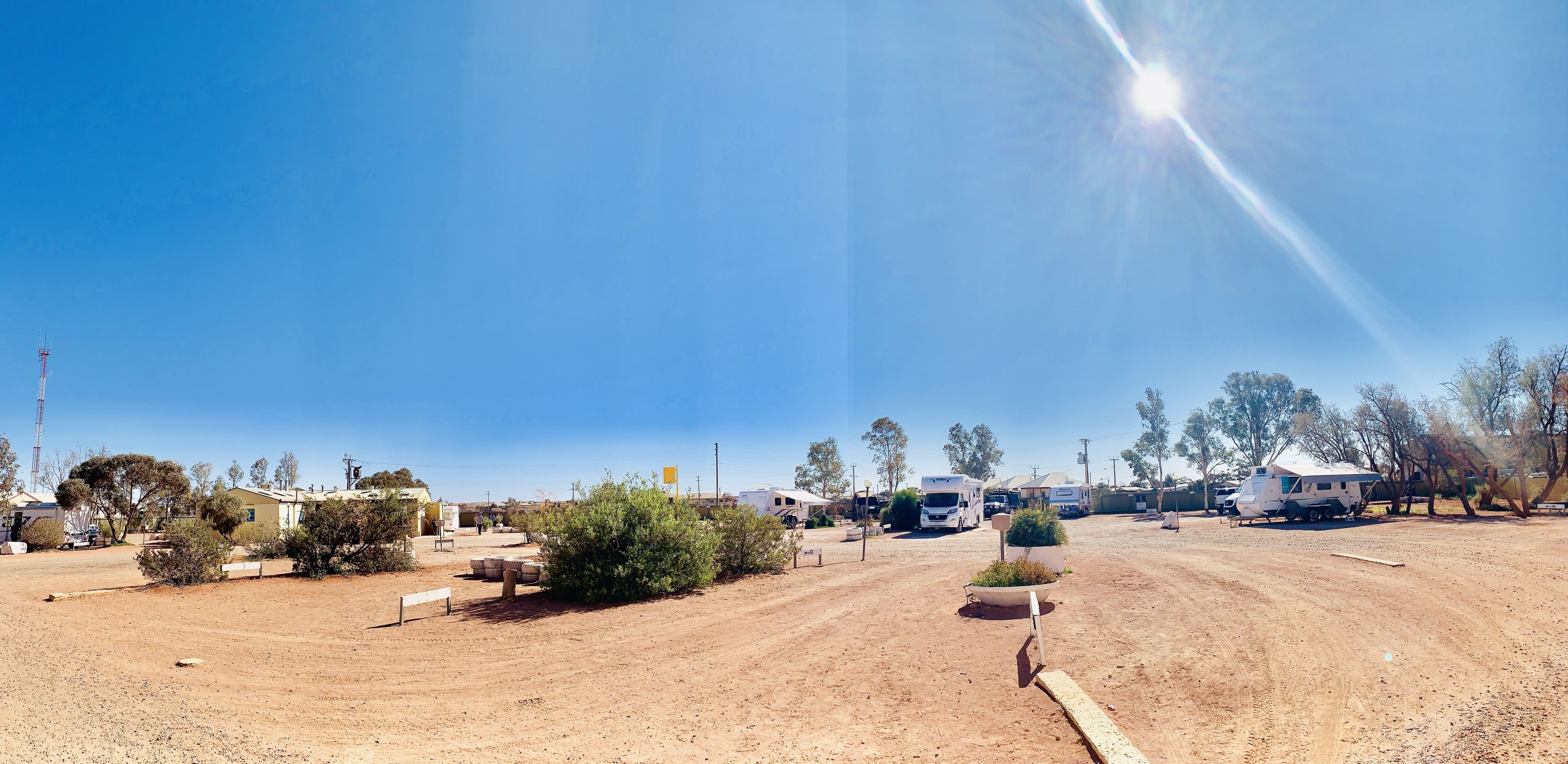 A campsite with RVs parked, a dirt road, and sparse vegetation.