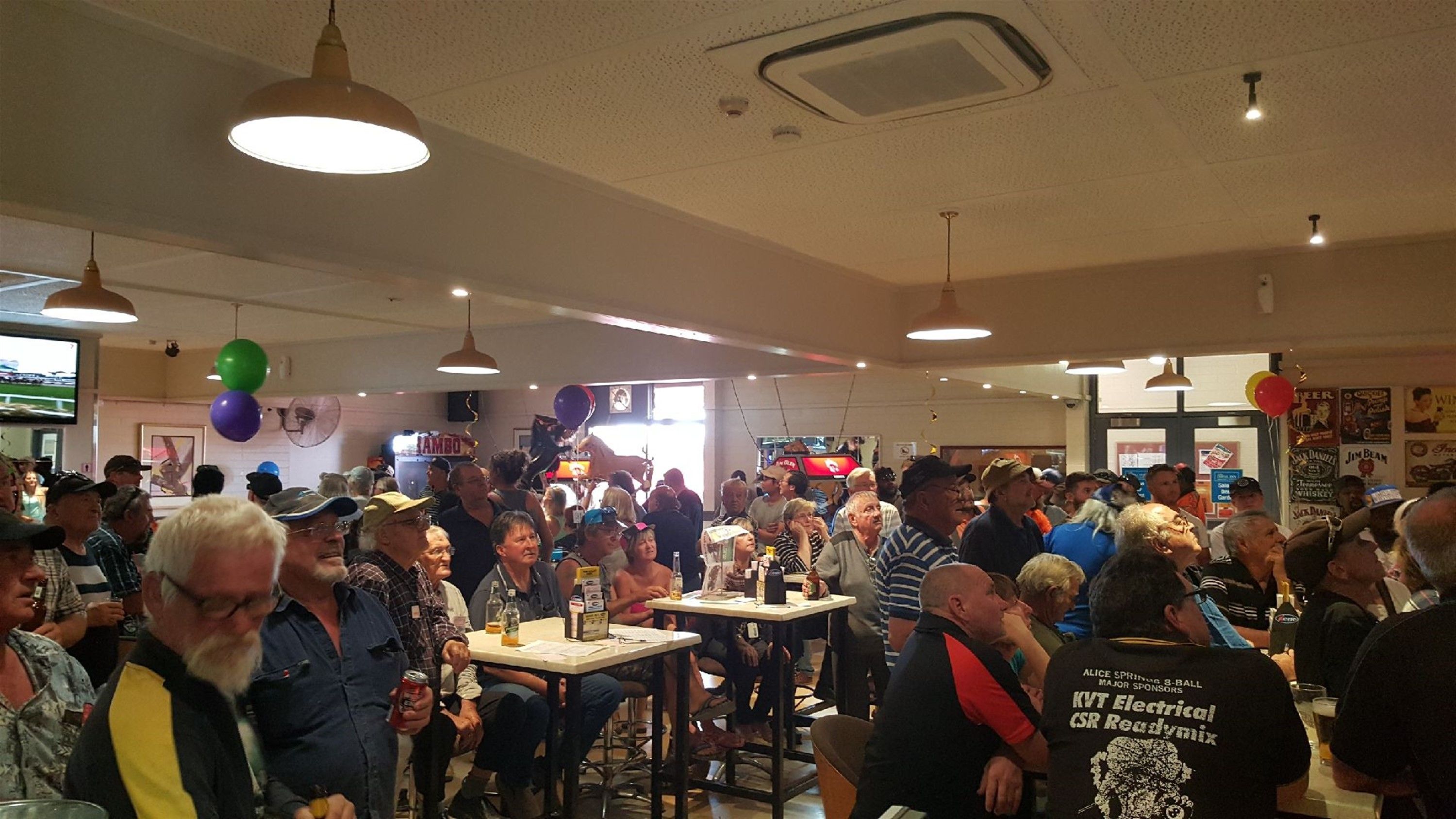 A crowded indoor space with tables and chairs, likely a restaurant or event venue.