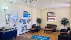 Un hall d’entrée avec un comptoir de réception, un espace salon et un paillasson sur lequel est écrit « Bienvenue ».