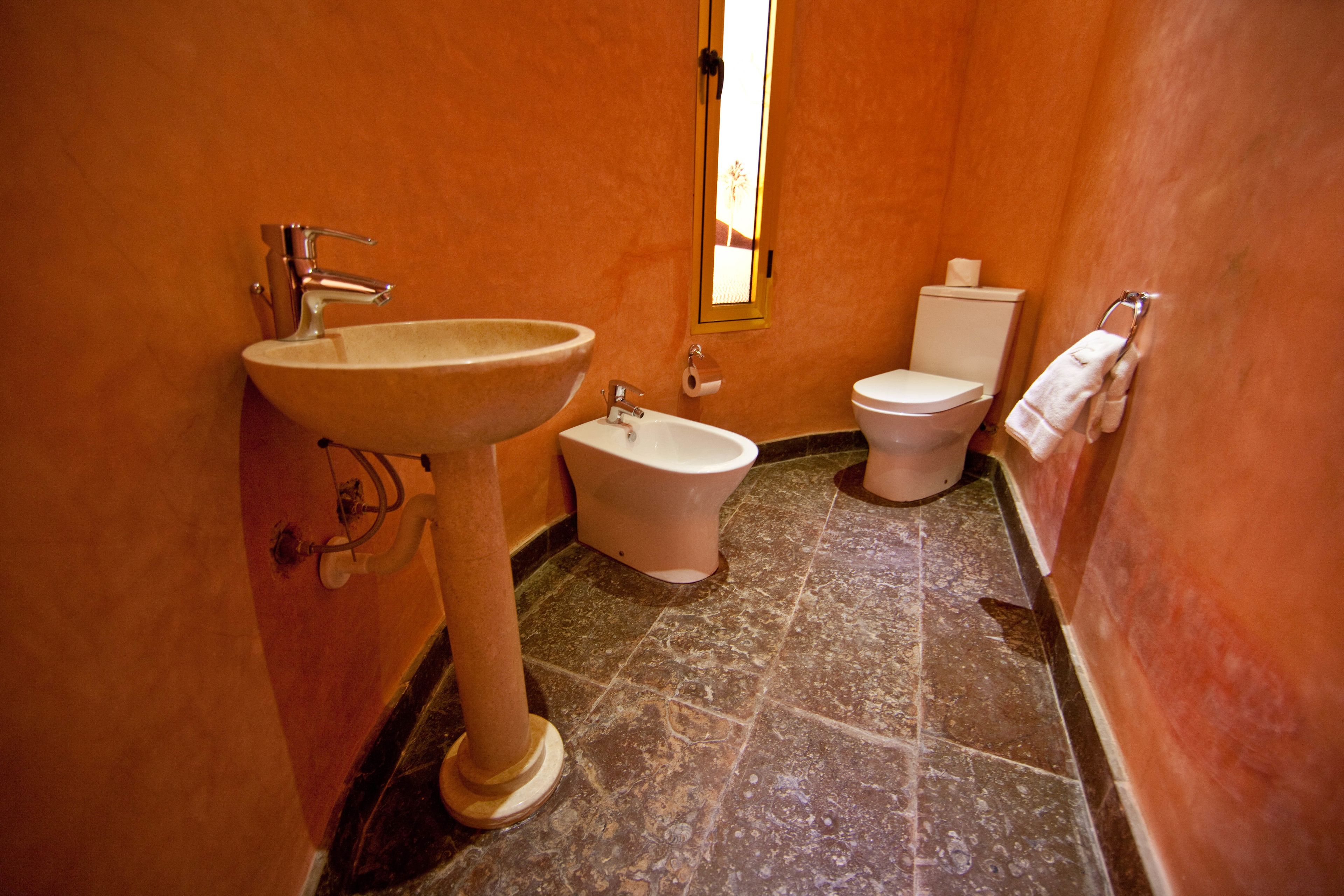 Une salle de bain équipée d’un lavabo, d’un bidet, de toilettes et d’une fenêtre donnant sur un paysage agréable.