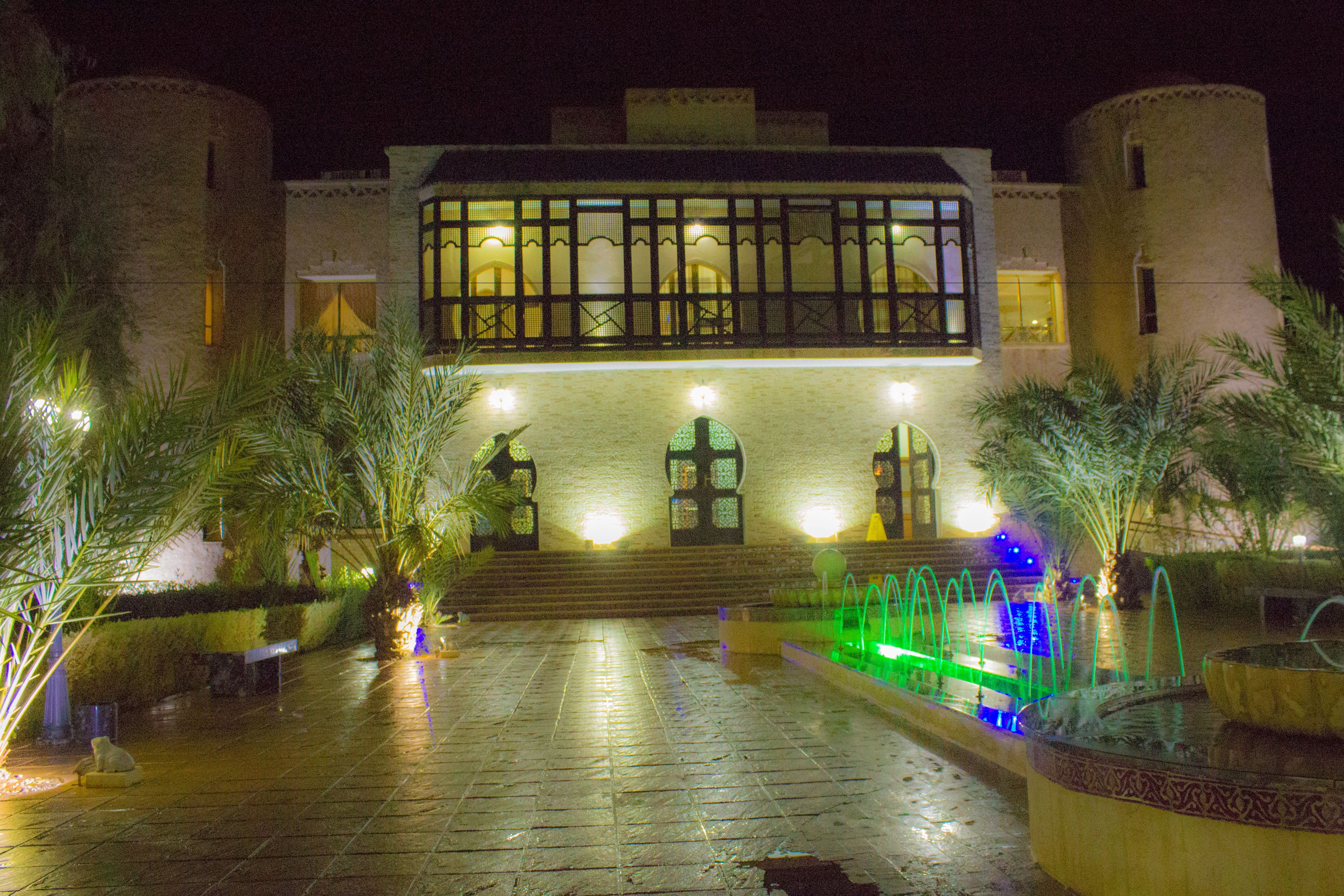 A historic building with a courtyard, illuminated windows, and a fountain.