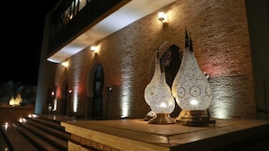 Fachada de edificio con pared de ladrillo texturizado, iluminada por luces empotradas y lámparas decorativas.