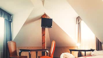 Ein Hotelzimmer mit Bett, Schreibtisch, Sessel, Fernseher und einer Chandelier.