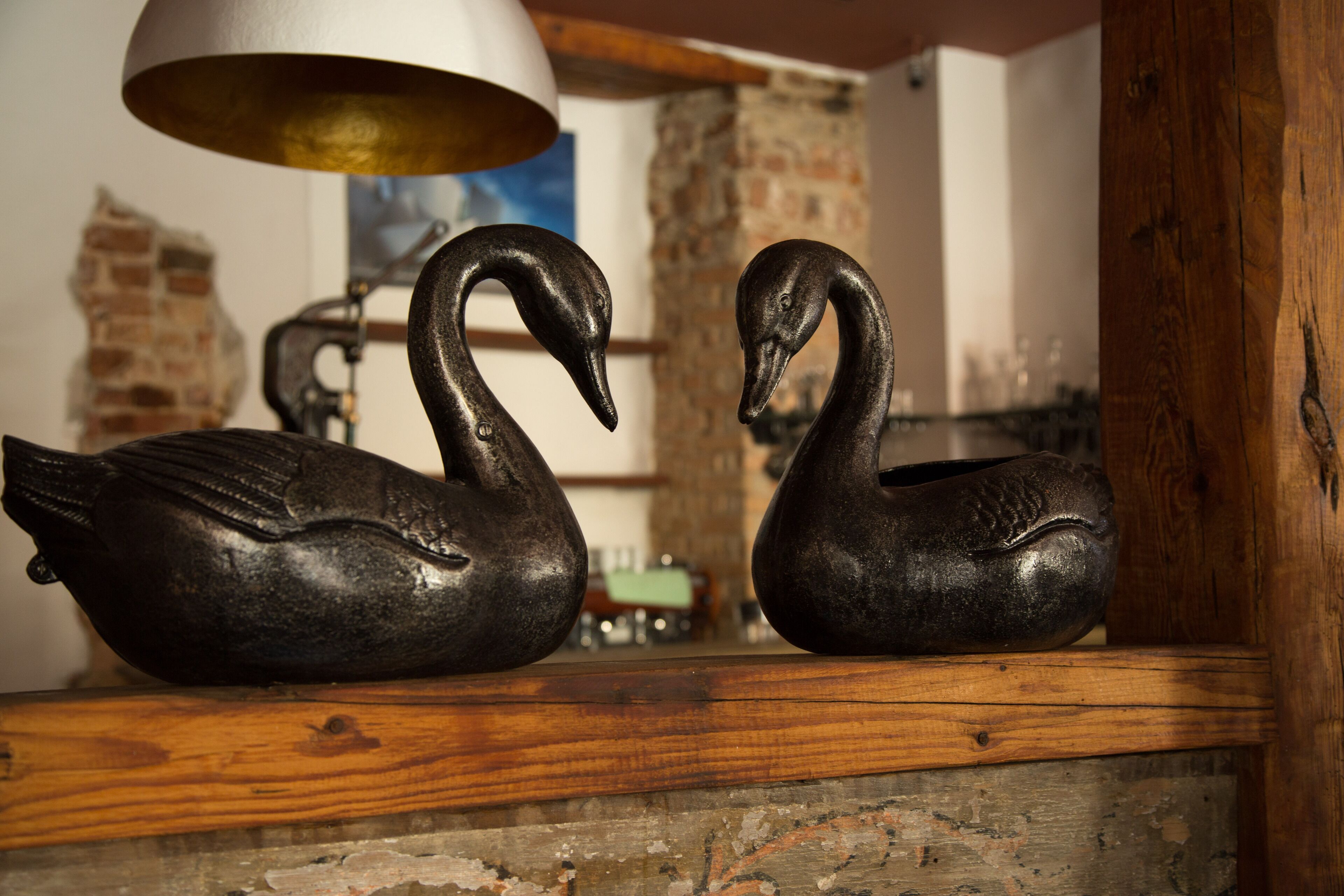 Dos esculturas de cisnes negros sobre una estantería de madera.