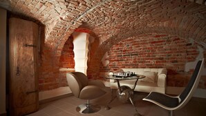 A room with a brick ceiling, a white sofa, a round table, and a modern chair.