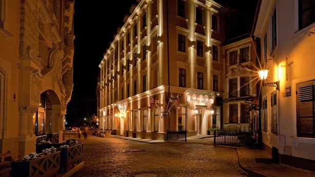A historic building with a central entrance, large windows, and a cobblestone street.