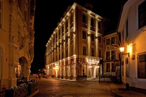 Un edificio histórico con una entrada central, ventanas amplias y una calle adoquinada.