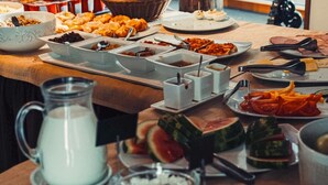 A buffet table with various food items and a pitcher of milk.