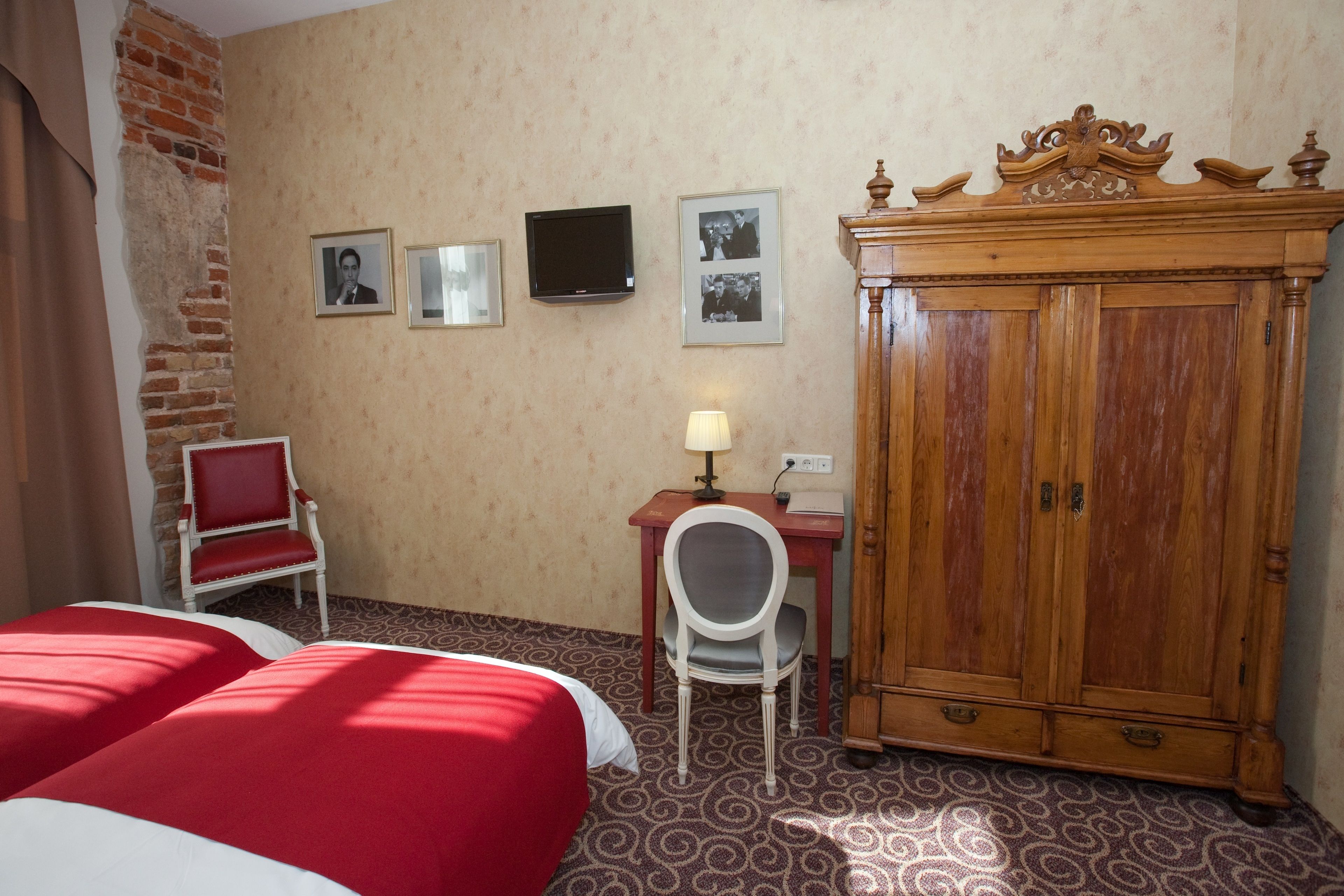 A hotel room with two beds, a desk with a chair, a television, and a wooden cabinet.