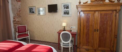 A hotel room with two beds, a desk with a chair, a television, and a wooden cabinet.