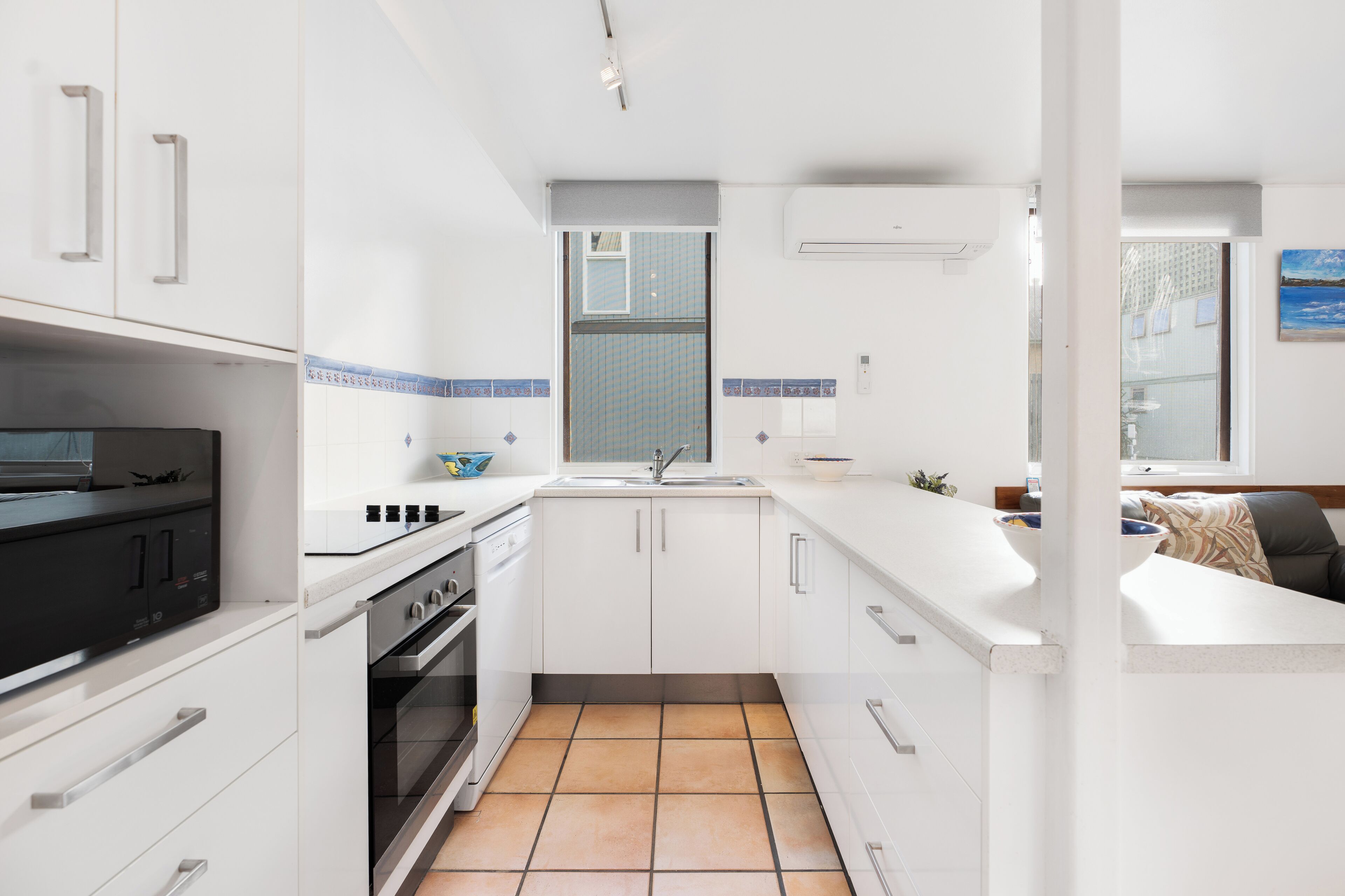 A compact kitchen with white cabinets, a black stove, and a tiled floor.