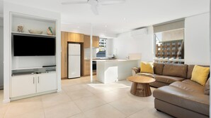 A modern living room with a sofa, a coffee table, and a TV on a stand. - The Hastings Beach Houses (Noosa Heads)