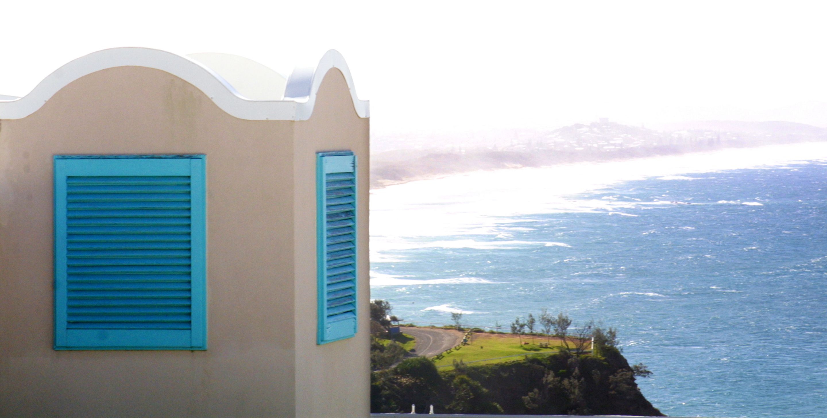 Edificio costiero con due persiane blu e vista sull'oceano.