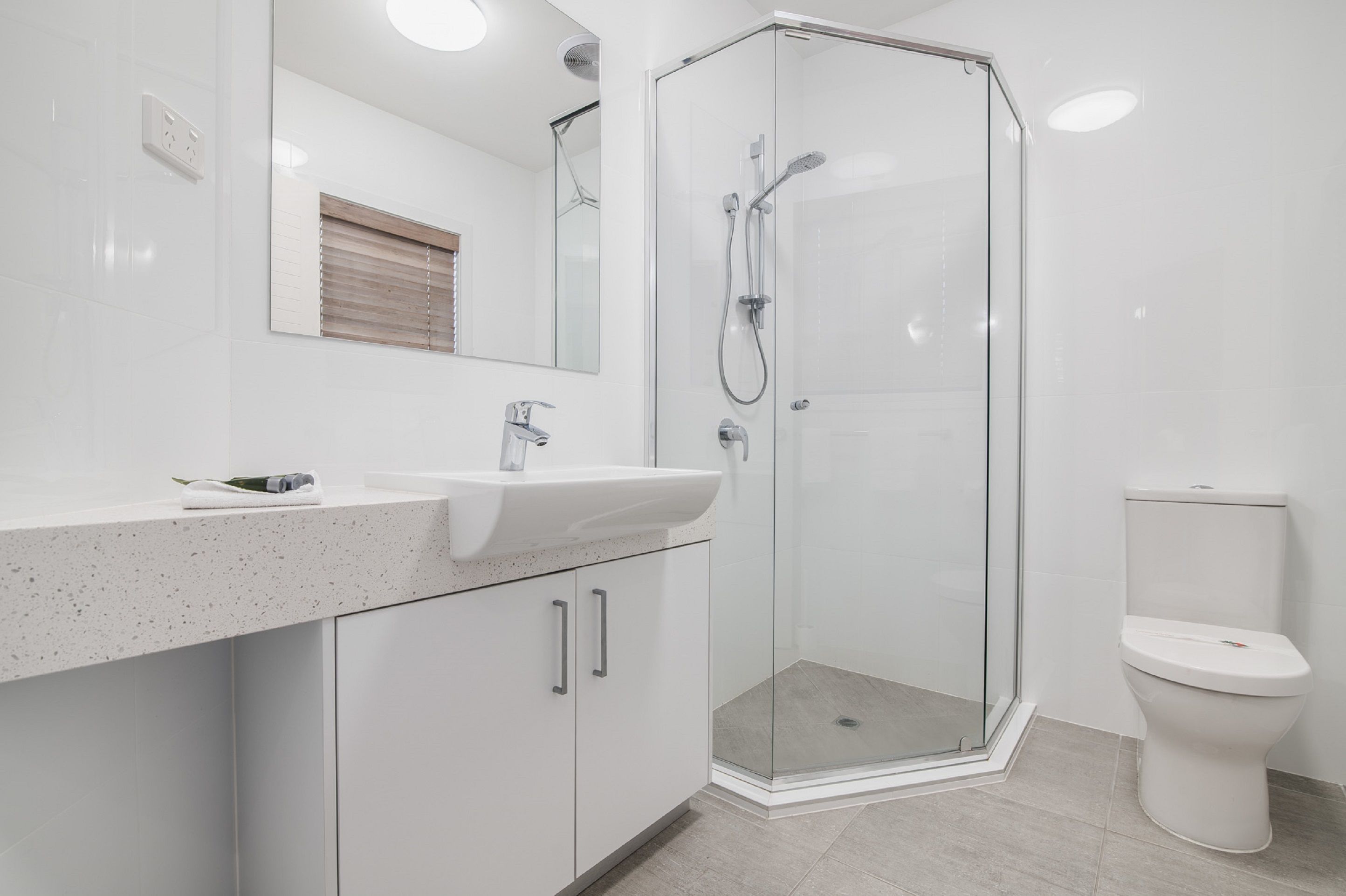 Ein modernes Badezimmer mit einer Glasdusche, einem weißen Waschbecken und einer Toilette.