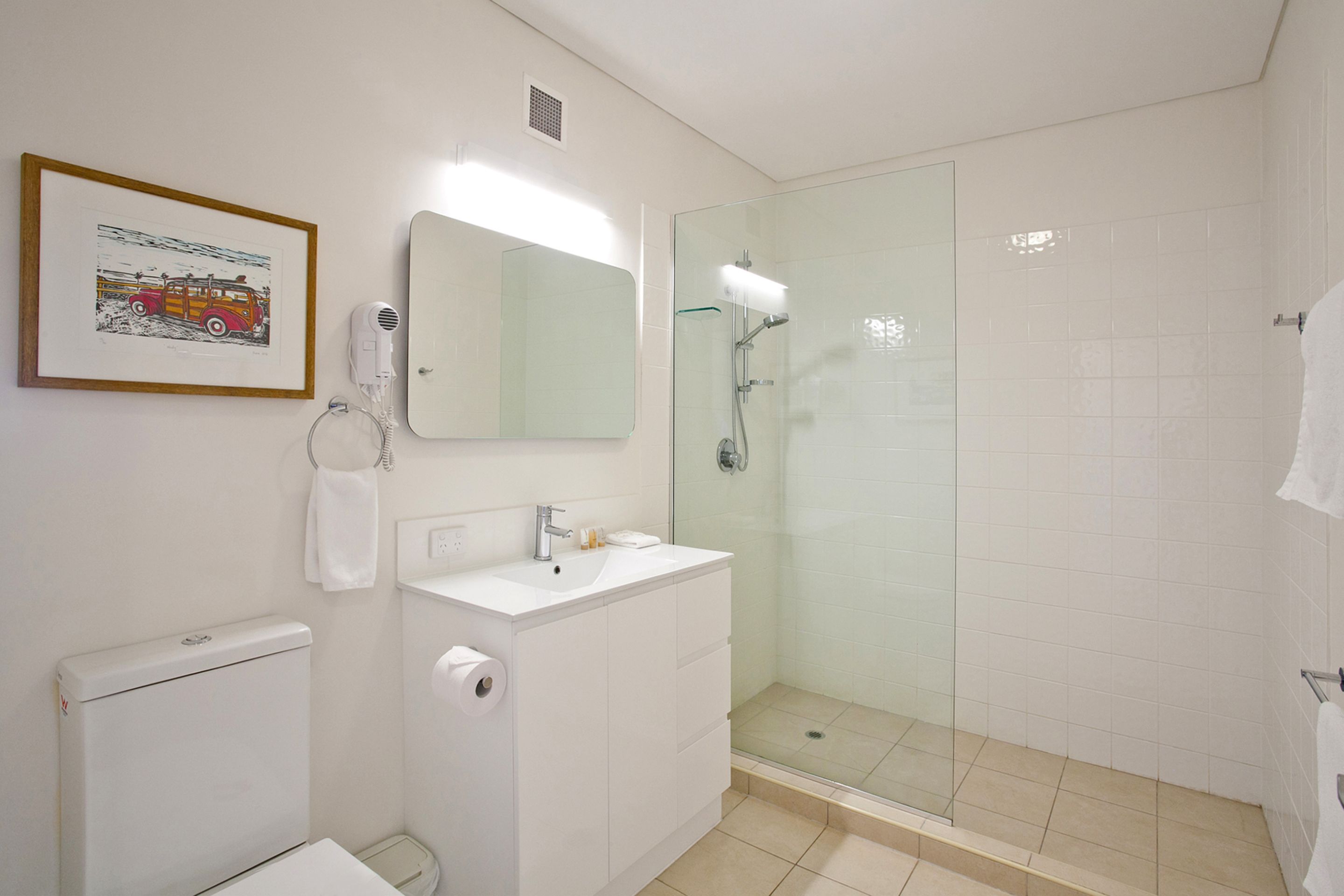 A bathroom with a white sink, mirror, and glass shower enclosure.